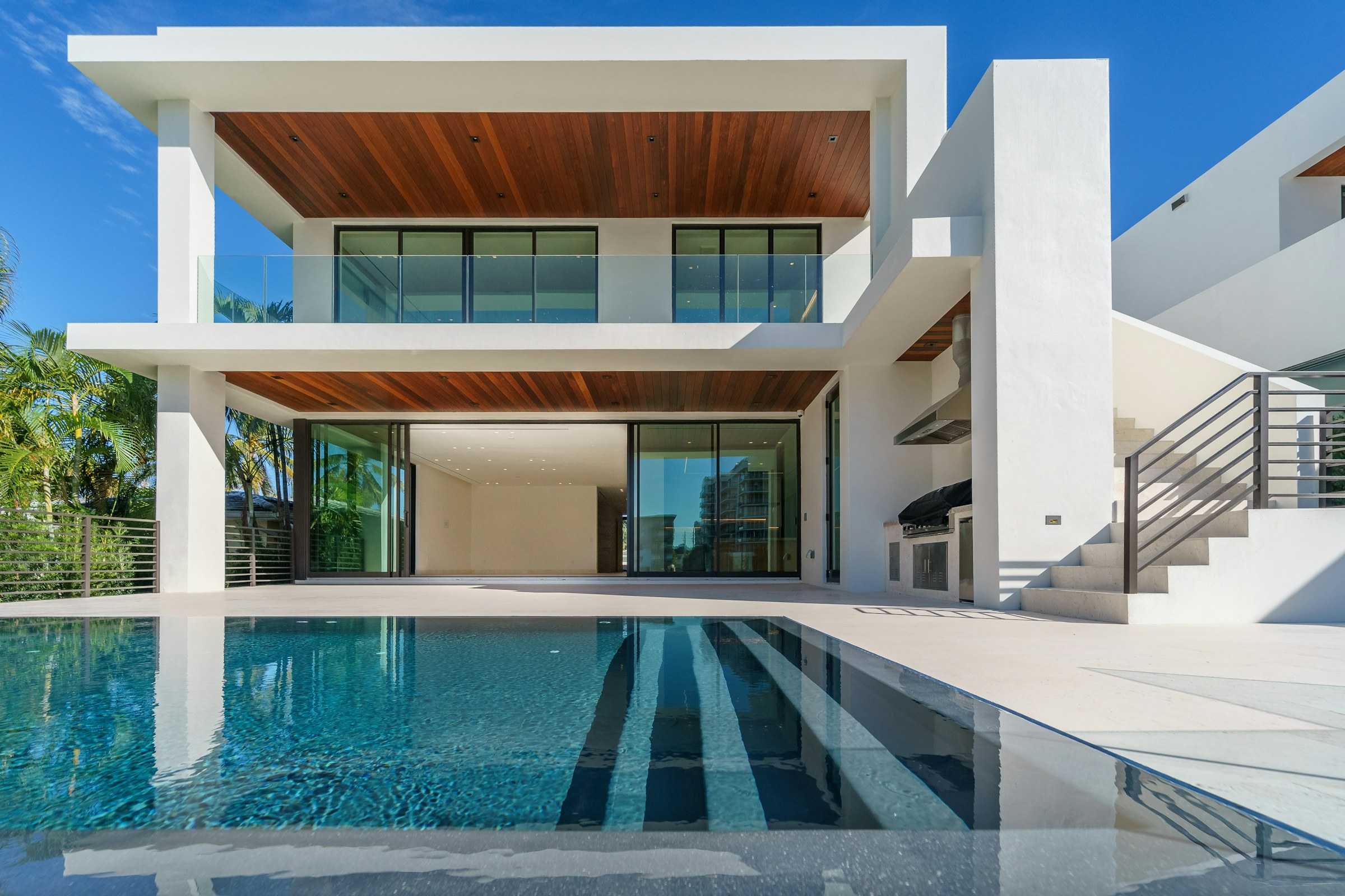 Rear elevation of a contemporary house with a linear pool and deep, shaded outdoor rooms
